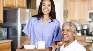 young-pretty-female-caregiver-serving-food-to-elderly-black-male